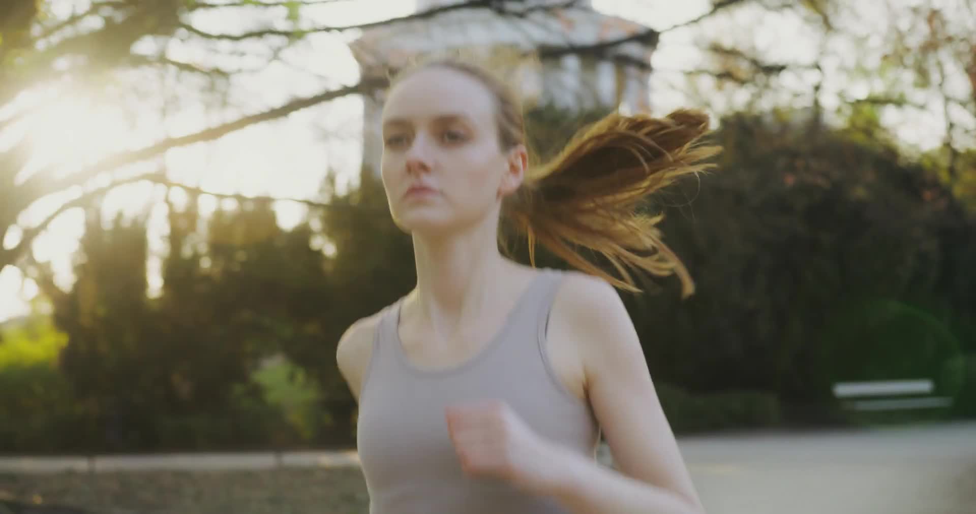 A person running along a tree-lined path in a park on a bright morning